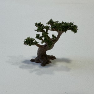 May include: A miniature model of a tree with a brown trunk and green leaves. The tree is on a white background.