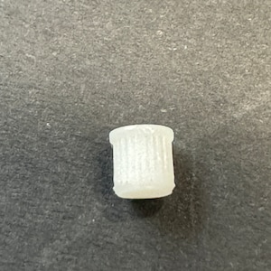 May include: White plastic trash can with a ribbed texture. The trash can is small and appears to be a miniature model.