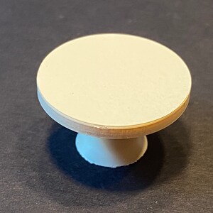 May include: A small, white, round pedestal table with a smooth, flat top.