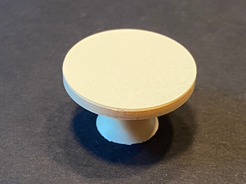 May include: A small, white, round pedestal table with a smooth, flat top.