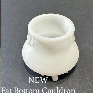 May include: White ceramic cauldron with a wide, round opening and three short legs. The cauldron is labeled "NEW Fat Bottom Cauldron".