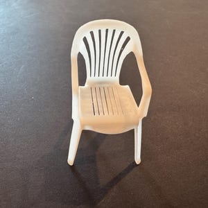 Op de afbeelding: Witte plastic buitenstoel met een lattenrug en zitting. De stoel heeft armleuningen en vier poten. De stoel is gemaakt van duurzaam kunststof en is geschikt voor gebruik buitenshuis. De stoel is lichtgewicht en gemakkelijk te verplaatsen.