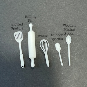 Puede incluir: Un juego de seis utensilios de cocina blancos, que incluyen una espátula ranurada, un rodillo, un batidor, una espátula de goma, una cuchara de madera para mezclar y un rodillo de madera.