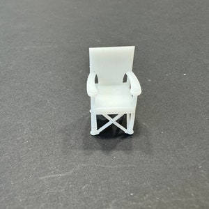 May include: A white folding chair with a simple design. The chair has a white fabric seat and a white metal frame.