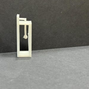 以下が含まれることがあります： 天井から丸い物が1つぶら下がっている、小さなオープンフレームの建物の白いプラスチックモデルです。