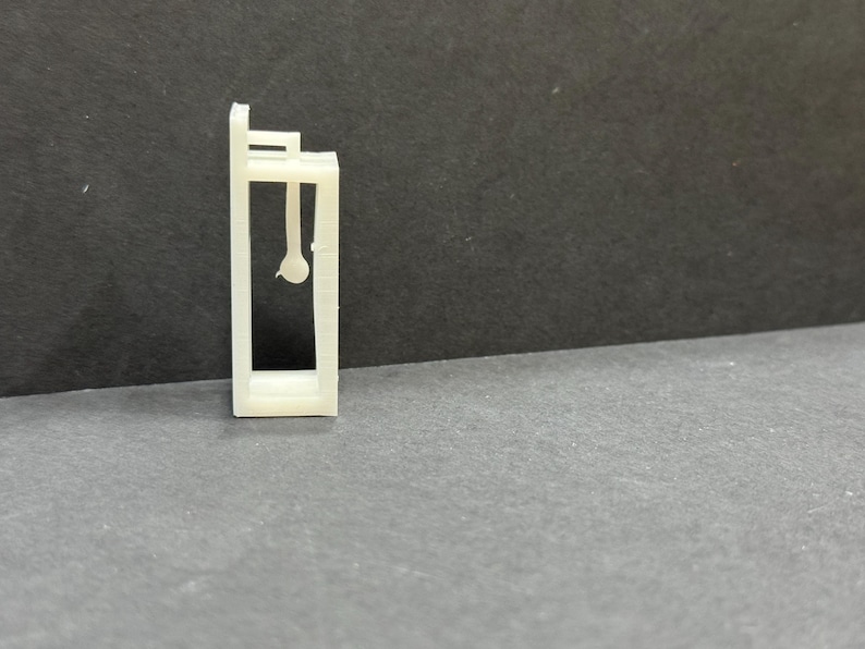 以下が含まれることがあります： 天井から丸い物が1つぶら下がっている、小さなオープンフレームの建物の白いプラスチックモデルです。