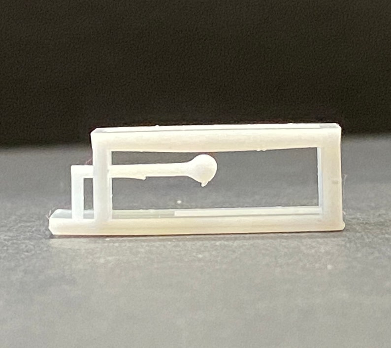 以下が含まれることがあります： 透明な窓が付いた白いプラスチック製のケースで、中に小さな白い物体が表示されています。