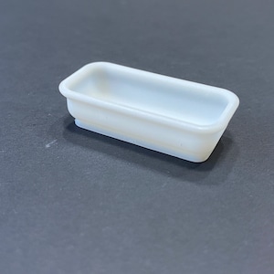 May include: A white rectangular plastic container with a smooth surface. The container is empty and has a slight curve to the sides.