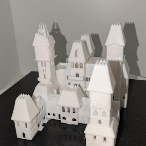 May include: A white 3D printed model of a castle with multiple towers and a clock face on each tower. The model is sitting on a black surface.