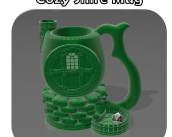 May include: A green ceramic mug shaped like a small house with a round window and a stone base. The mug has a handle shaped like a curved branch. A single green dice is in the small fenced area in front of the mug.