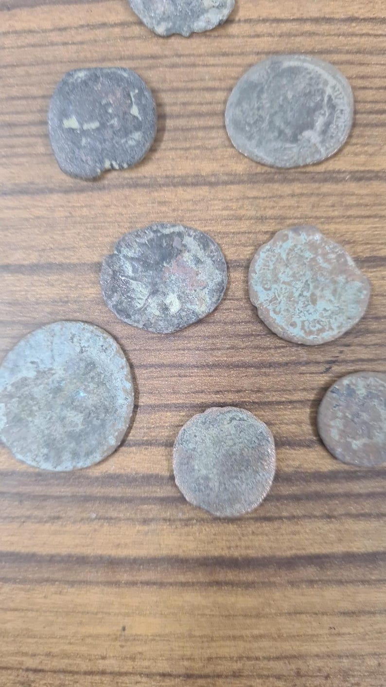 Puede incluir: Una colecci&oacute;n de ocho monedas antiguas de plata con diferentes grados de desgaste y p&aacute;tina. Las monedas est&aacute;n dispuestas sobre una superficie de madera.