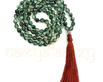 May include: A green agate mala with a brown tassel. The mala is made of 108 beads and is used for meditation and prayer.