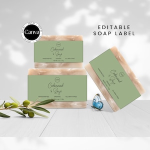 May include: Three bars of handmade Cedarwood & Sage soap, each with a green label and the text "Cedarwood & Sage" in a handwritten font. The soap is organic and suitable for all skin types. The bars are stacked on a white wooden surface with a green olive branch and a blue butterfly.