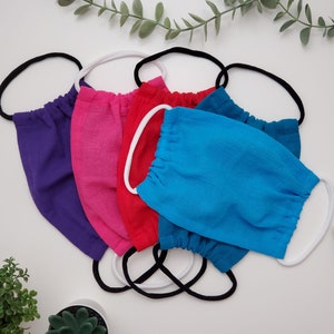 May include: Six fabric face masks in a variety of colours, including purple, pink, red, and blue. The masks are made from a soft, breathable material and have elastic ear loops.