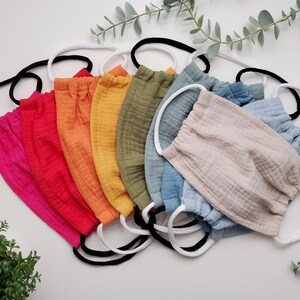 May include: A set of ten face masks in various colours, including pink, red, orange, yellow, green, blue, and beige. The masks are made of a soft, breathable fabric and have elastic ear loops.