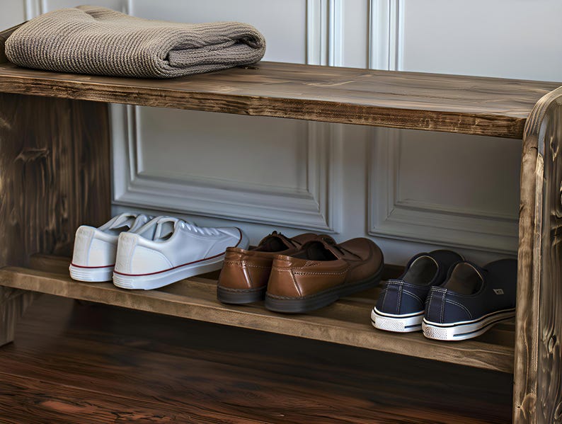 May include: A rustic wooden shoe bench with two shelves. The top shelf holds a folded beige blanket. The lower shelf displays pairs of white sneakers, brown leather loafers, and navy canvas shoes.