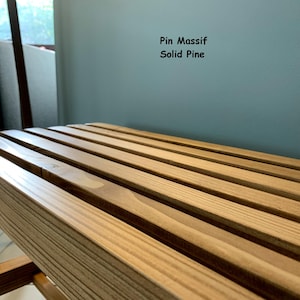 Gros plan en angle sur l'assise à lattes en pin massif du banc, avec le texte Pin Massif Solid Pine affiché en haut à droite.