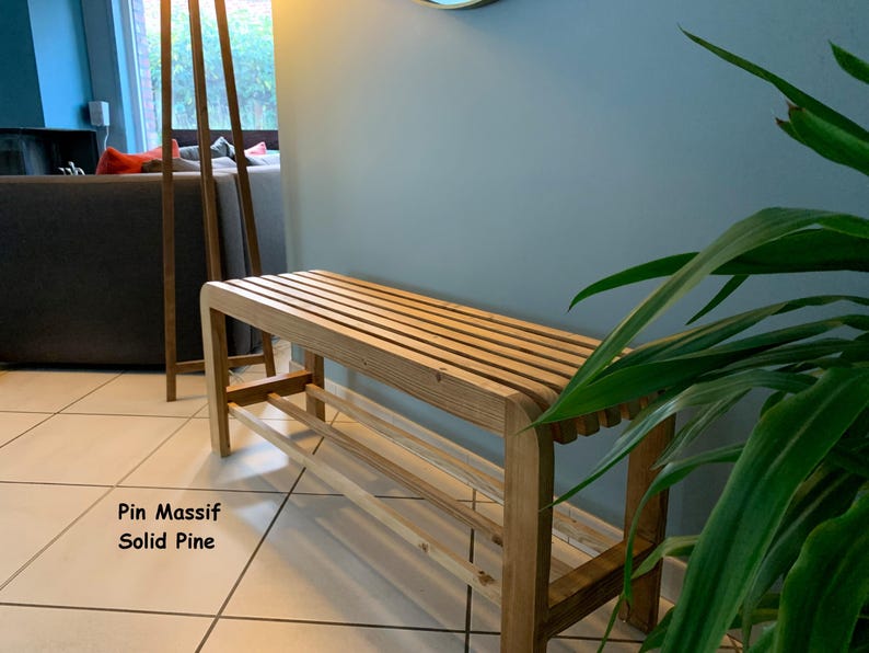 Un banc à chaussures en pin massif installé dans une pièce lumineuse près d'une plante verte, avec le texte Pin Massif Solid Pine incrusté.