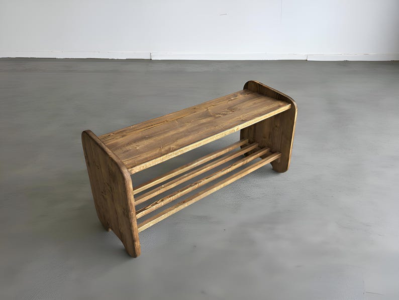 May include: A wooden shoe rack with a natural finish. The rack has a top shelf and a lower shelf with three horizontal slats for shoe storage. The sides of the rack are curved, and the wood grain is visible.