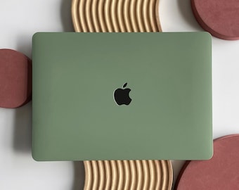 以下が含まれることがあります： 木製のスタンドの上に置かれた、緑色のアップルロゴが付いたノートパソコン。ノートパソコンの周りは、赤い丸いコースターが3つ置かれている。