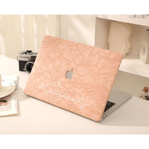 Può includere: Una custodia per laptop rosa chiaro con un motivo floreale e la parola "remarkable" scritta in bianco.