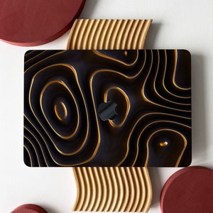 May include: A black laptop skin with a gold abstract design. The skin has a wavy, flowing pattern that resembles liquid gold.