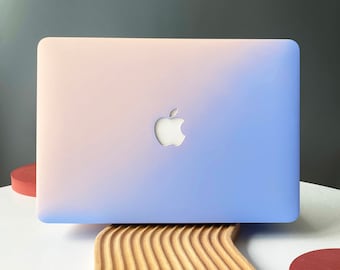 May include: A light blue and pink laptop with a white Apple logo on the lid. The laptop is sitting on a wooden stand with a wavy design.