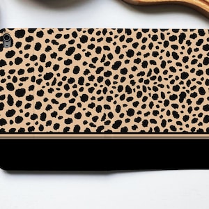 Può includere: Una custodia per iPad con stampa leopardata marrone e nera con un bordo nero.