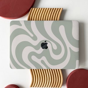 May include: A laptop computer with a green and white swirl pattern on the lid. The laptop is sitting on a wooden stand with a red circle on either side.