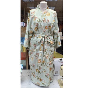 May include: A light green floral patterned robe with a matching belt. The robe features a classic kimono style with wide sleeves and pockets. The floral pattern includes pink, yellow, and brown flowers on a light green background.