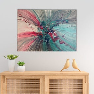 Könnte beinhalten: Abstraktes Gemälde in Rosa-, Türkis- und Grautönen. Das Gemälde hängt an einer Wand über einem Schrank aus Holz mit zwei Türen.