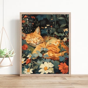 May include: A framed art print featuring a sleeping orange tabby cat nestled among colorful flowers and greenery. The artwork has a vintage aesthetic with a wooden frame. Two hanging planters with succulents are also visible.
