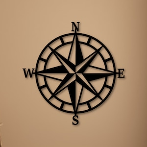 May include: Black metal compass with a star design and the letters N, S, E, and W.
