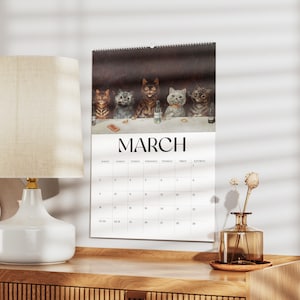 May include: A wall calendar for March featuring a humorous illustration of cats at a table. The image shows six cats with various fur patterns. The word "MARCH" is printed in large, bold letters above the calendar grid.