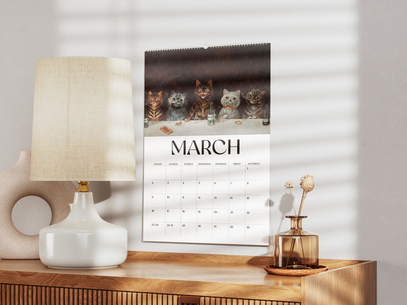 May include: A wall calendar for March featuring a humorous illustration of cats at a table. The image shows six cats with various fur patterns. The word "MARCH" is printed in large, bold letters above the calendar grid.