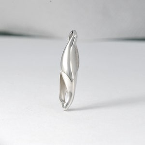 May include: A silver pendant shaped like a twisted, abstract form. The pendant is smooth and polished, with a contemporary design.