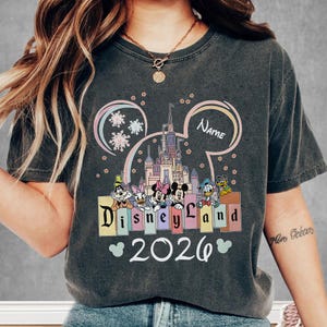 A person wearing a t-shirt with a Disney theme and the text "Disneyland 2026" printed on it.