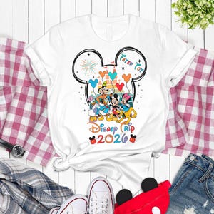 A white t-shirt with a Disney-themed graphic design, featuring Mickey Mouse and other Disney characters, is displayed on a white background.