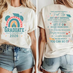 a white t-shirt with a graphic design and text on it. The design includes a castle and a rainbow, and the text on the back of the t-shirt reads "Graduate - From the tent to the castle - 2026".