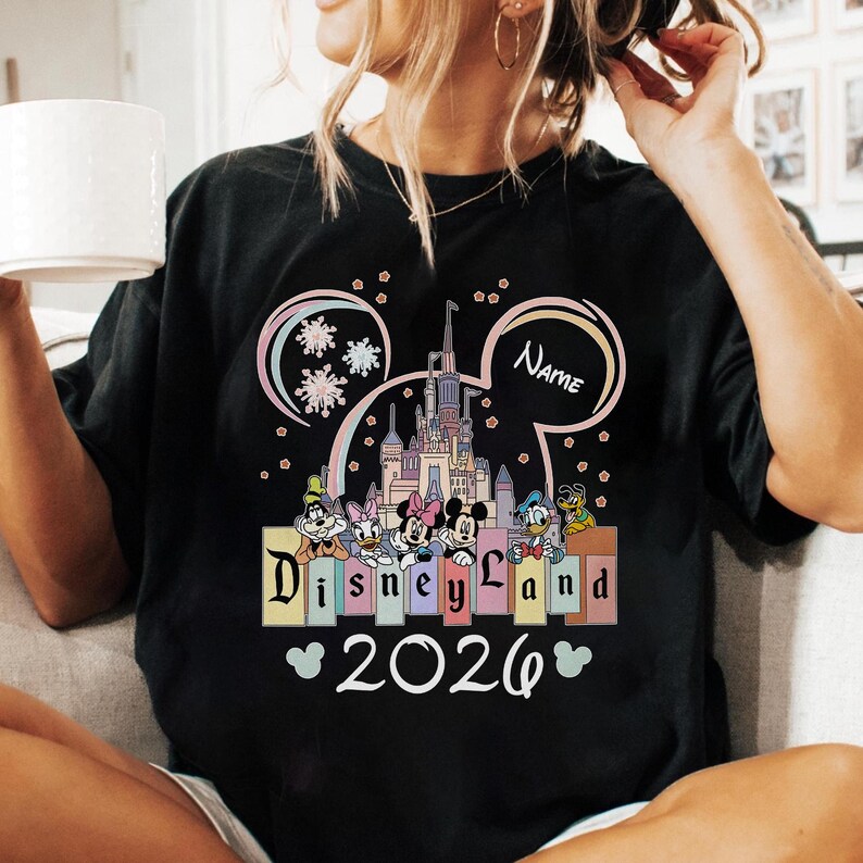 A person wearing a black t-shirt with a Disney Land-themed graphic and the text "Disneyland 2020" printed on it.