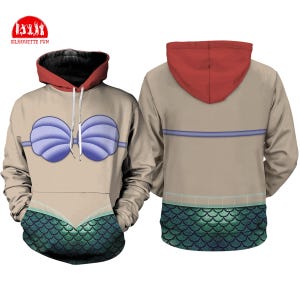 May include: A tan hoodie with a red hood and black lining. The front features a blue seashell bra design and a green scale pattern at the bottom. The back has a horizontal blue stripe and a green scale pattern.