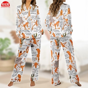 May include: White pajama set with an all-over print featuring cartoon characters, text, and various graphics. The long-sleeved top and pants have white piping. The text includes phrases like "It's making me mad" and "Sneaky Sneaky."