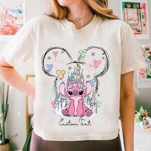 a woman wearing a mickey mouse shirt with a castle on it