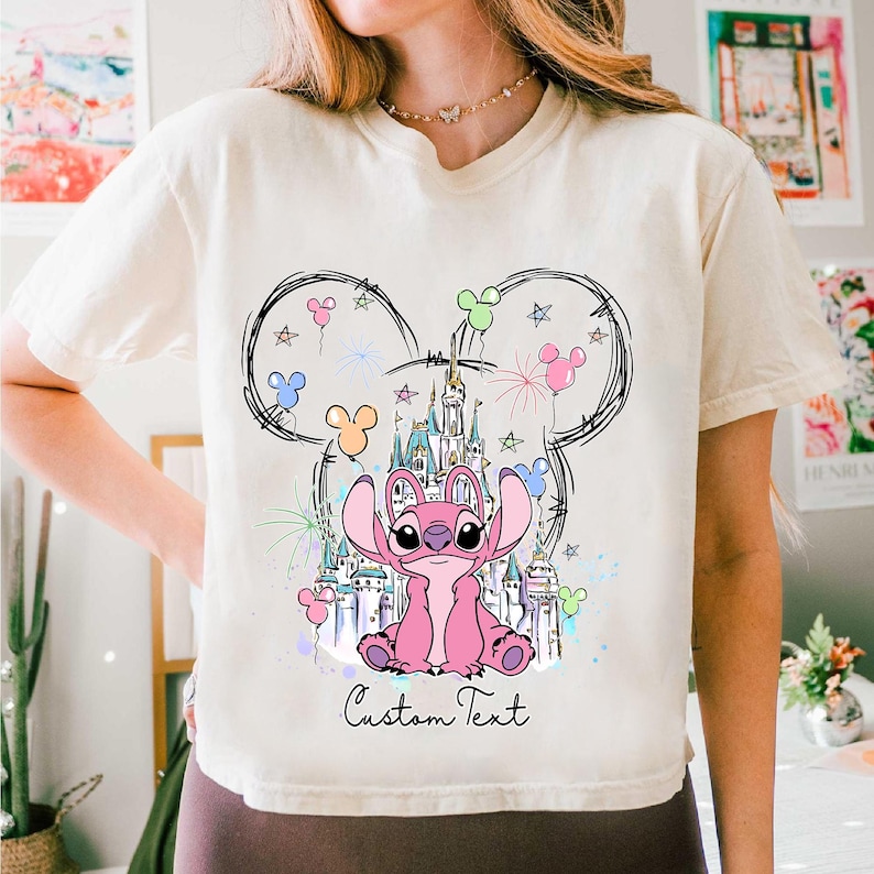 a woman wearing a mickey mouse shirt with a castle on it