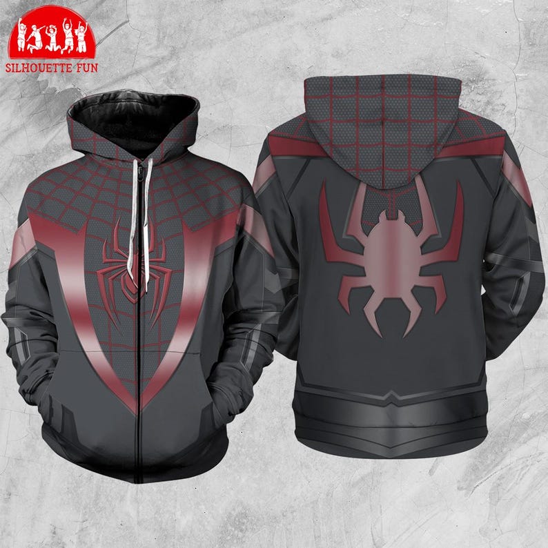 Pode incluir: Um casaco com capuz cinzento com fecho de correr, com um design de teia de aranha vermelha e um grande emblema de aranha na frente e atr&aacute;s. O casaco tem capuz e fecho de correr completo. O design lembra uma fantasia de super-her&oacute;i.