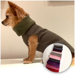 Könnte beinhalten: Eine braune Hundeweste mit einem grünen Fleece-Rollkragen. Ein kreisförmiger Einsatz zeigt einen Stapel Stoffmuster in verschiedenen Farben, darunter Grau, Braun, Schwarz, Lila, Rosa und Rot, die die verfügbaren Materialoptionen darstellen.