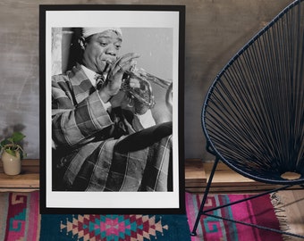 Puede incluir: Una impresión fotográfica enmarcada en blanco y negro que muestra a un músico con un traje de cuadros y un pañuelo en la cabeza mientras toca la trompeta. El retrato captura al sujeto en una pose concentrada, destacando el patrón del tejido.