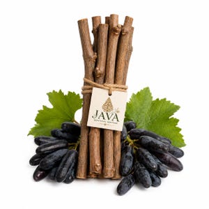 May include: A bundle of brown wooden sticks tied with twine, featuring a square tag printed with the text JAVA BOTANICAL HERITAGE and a gold leaf icon. The bundle is positioned in front of a cluster of dark purple grapes with green leaves.