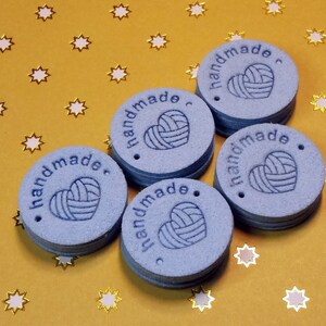 May include: Six blue round handmade tags with the text "handmade" and a heart with yarn inside. The tags have a hole punched in the top.