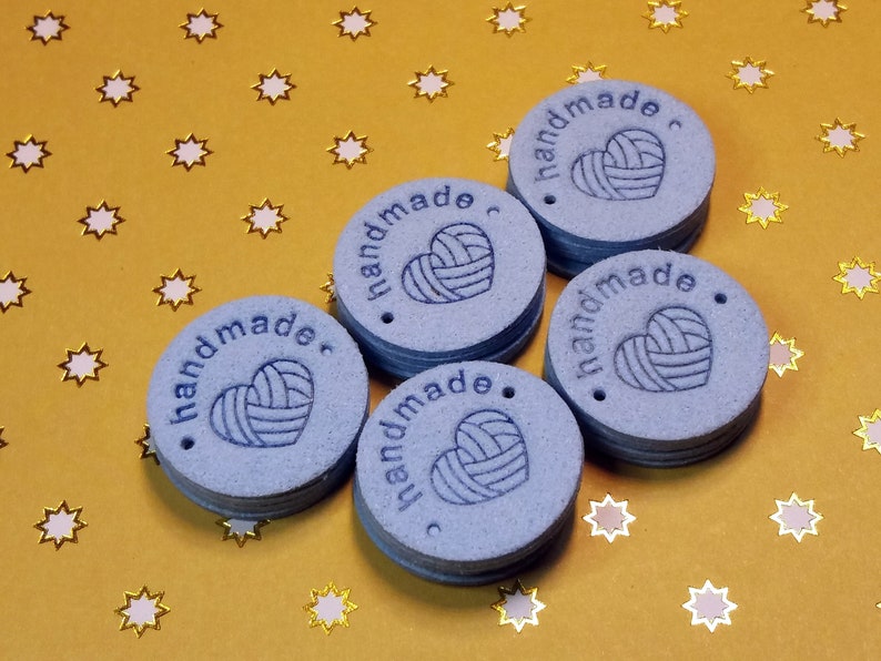 May include: Six blue round handmade tags with the text "handmade" and a heart with yarn inside. The tags have a hole punched in the top.